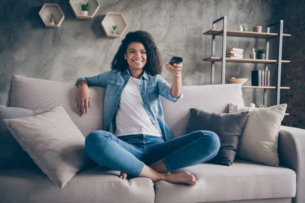 pretty lady holding tv remote control changing channel