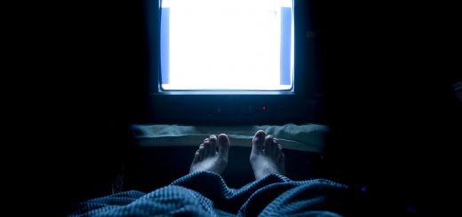 person watches TV at night in his bed