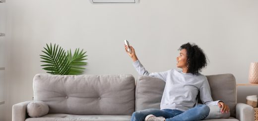 Smiling African American woman using air conditioner remote controller