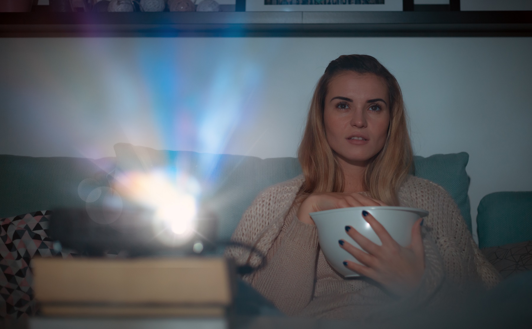 Woman on sofa watching movie using digital LCD video projector