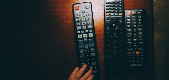 three black remote controls on wooden table