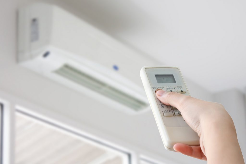 Hand with remote control directed on air conditioner