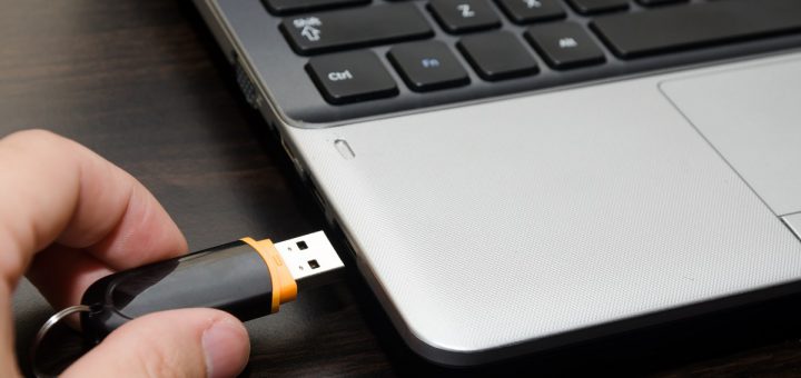 hand with usb flash drive inserting it into laptop computer closeup