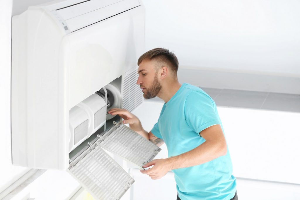 Young man fixing air conditioner at home