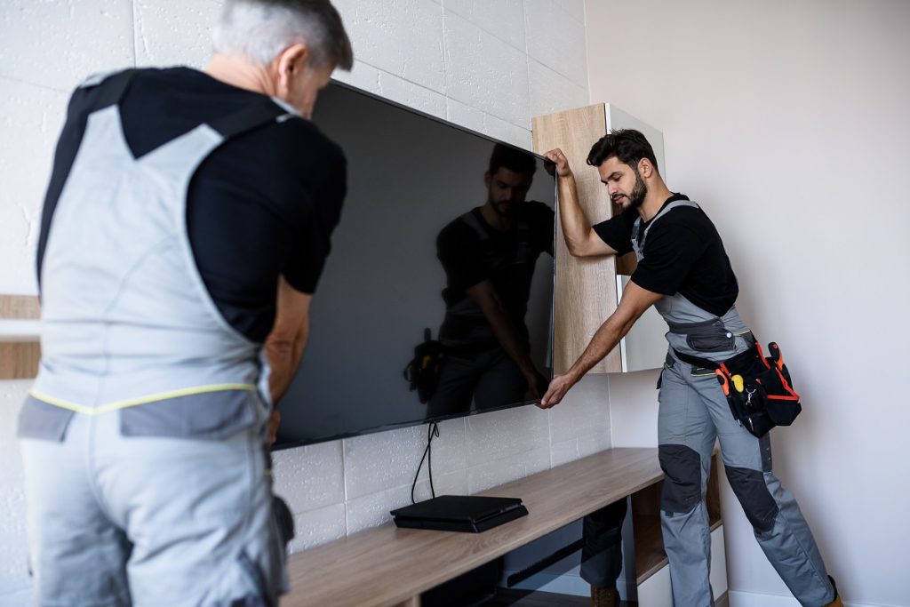 Two professional technicians workers installing television on the wall