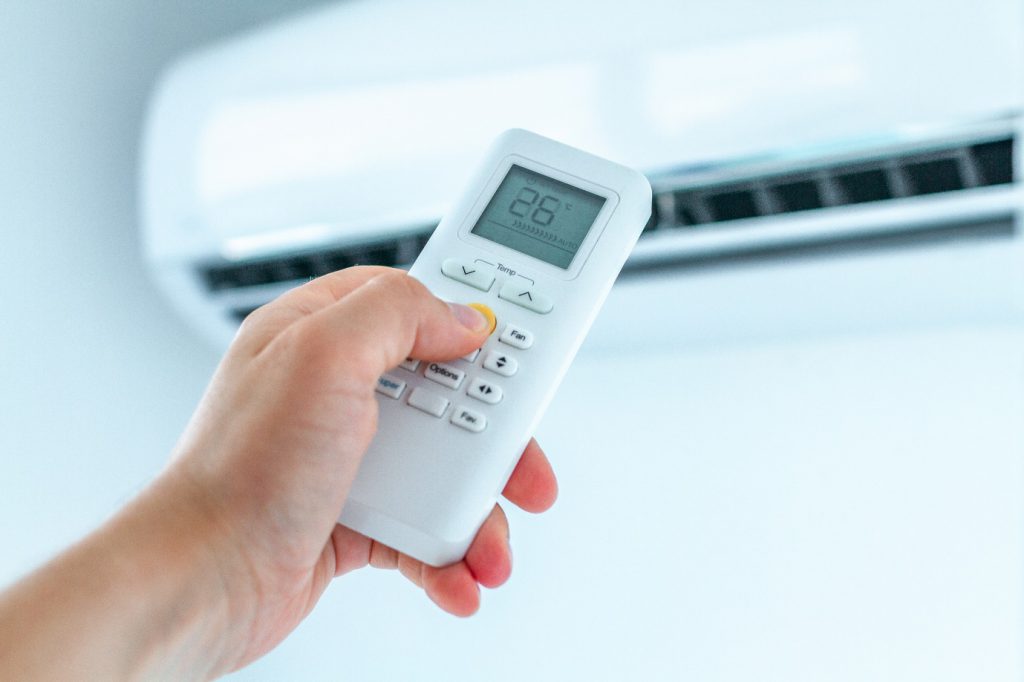 Air conditioner temperature adjustment with remote controller in room at home