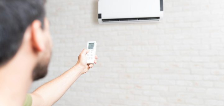Man adjusting temperature of air conditioner