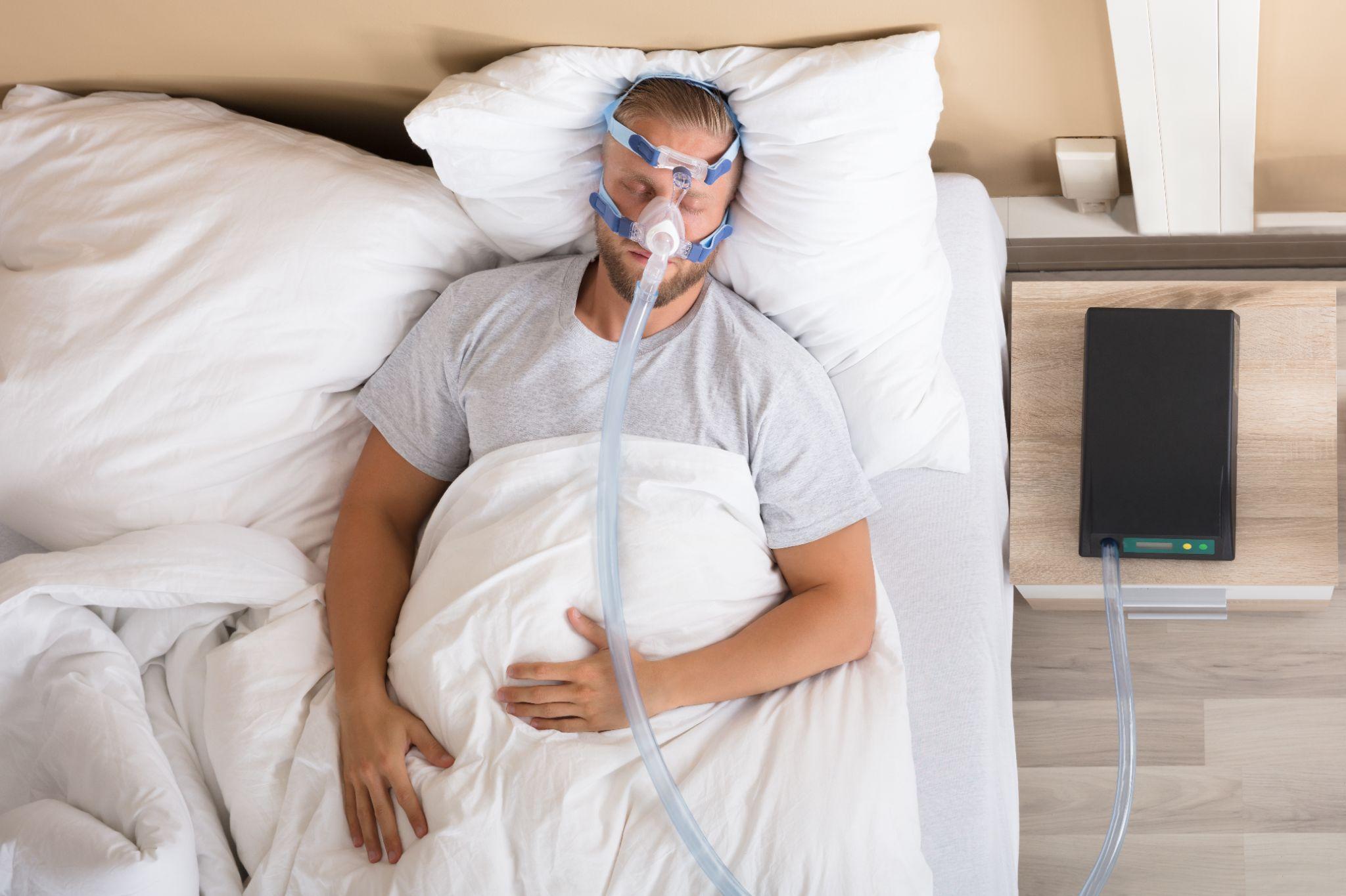 man sleeping in bed using a CPAP machine