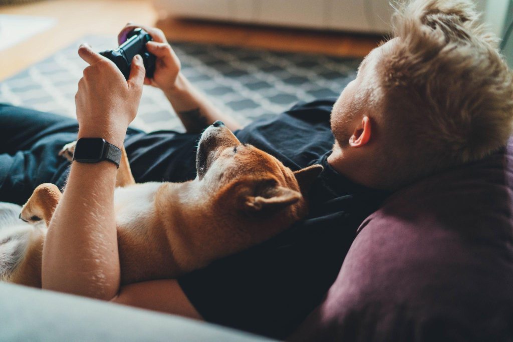 Young guy playing Xbox video games at home holding game joystick